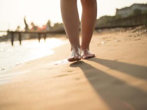 Detail of female barefoot feet on sunny beach