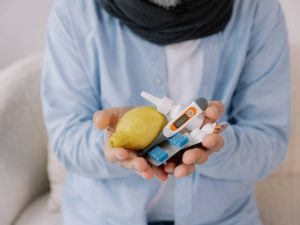 Senior gray bearded excited man in scarf having acute viral infection holding many anti-inflammatory drugs in hands in living room at home