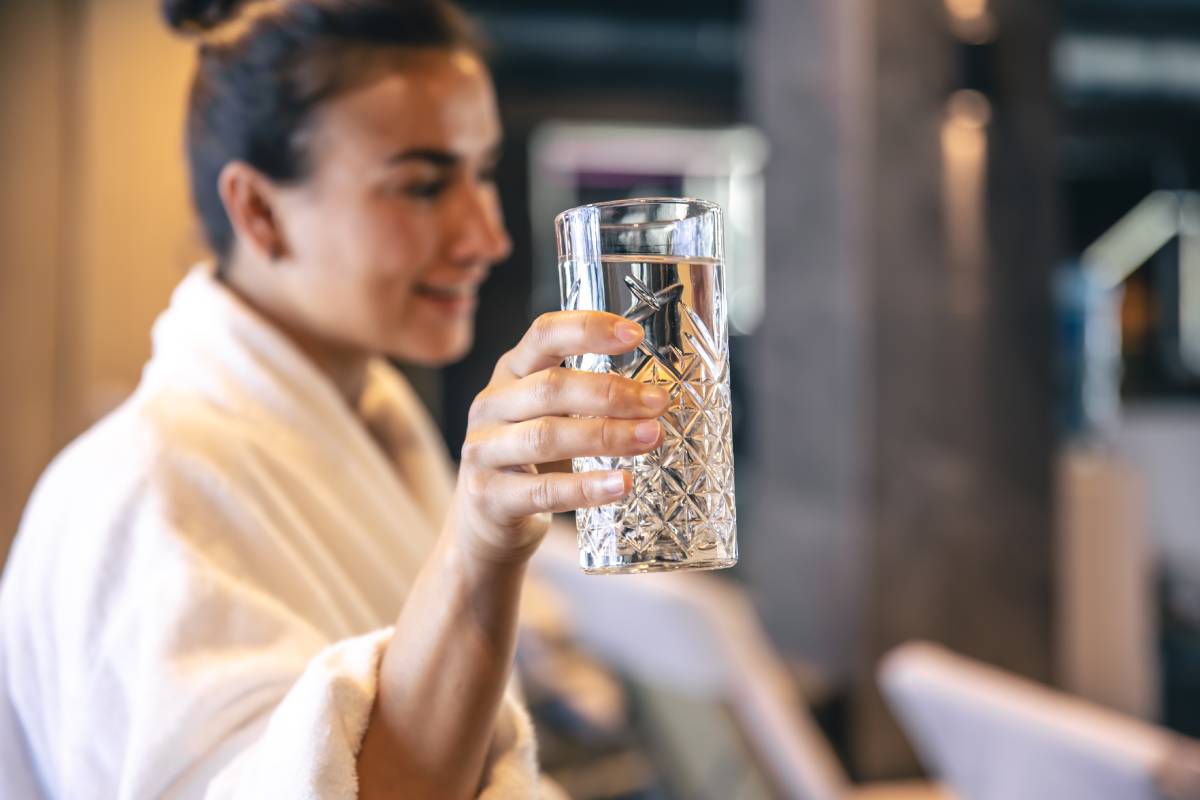 A young woman with a glass of water after the sauna is resting.