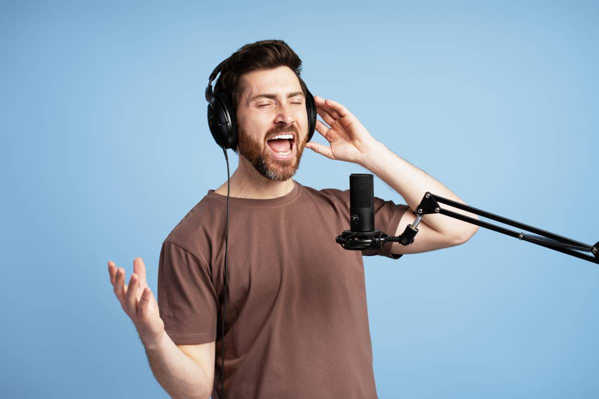 Singer wearing headphones singing with passion into microphone in recording studio
