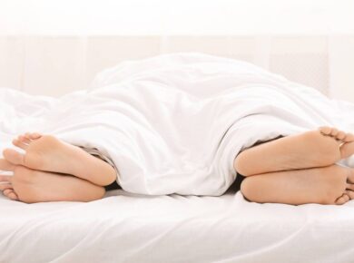 Relationship crisis. Bare feet of couple sleeping separately in bed, free space